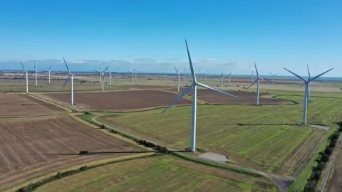 PA Media An aerial view of a number of onshore wind turbines located on green fields