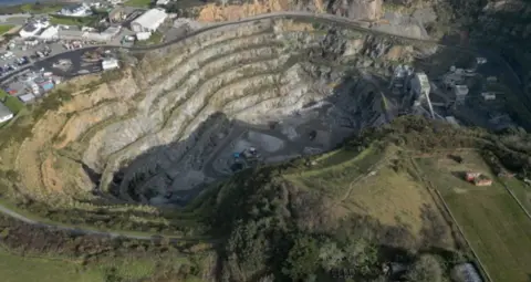 Les Vardes quarry from above. A large hole with a number of ribs moving down. 