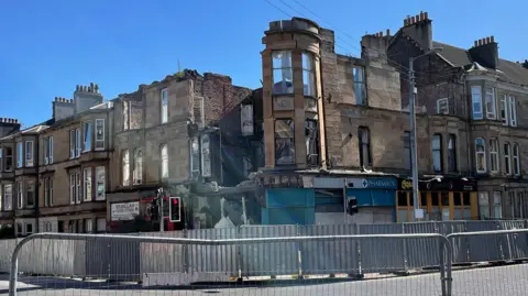 A collapsed building with fencing in the foreground