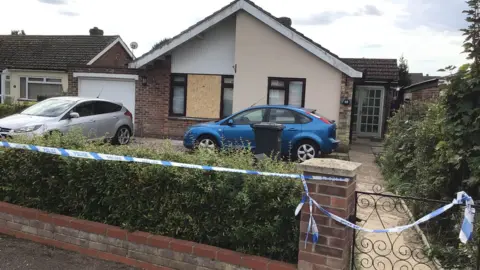 Richard Daniel/BBC Police at the scene where the woman and child were found dead