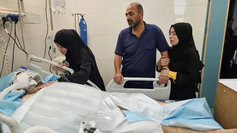 Alaa al-Najjar (2nd L) visits her husband (L) in Nasser hospital