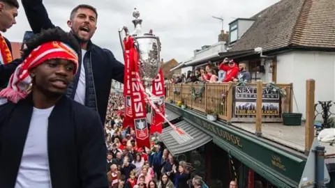 Jack Valpy/BBC A man holding the FA Vase and cheering.