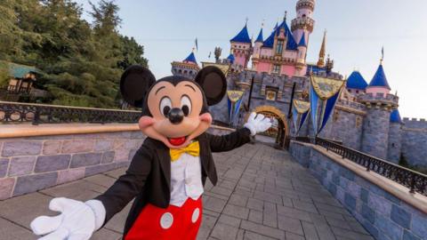 Mickey Mouse poses in front of Sleeping Beauty Castle at Disneyland Park