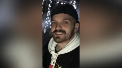 Juliano Scibelli A smiling Juliano Scibelli looks directly at the camera. He is wearing a black jacket, white hoodie and black backwards cap. 