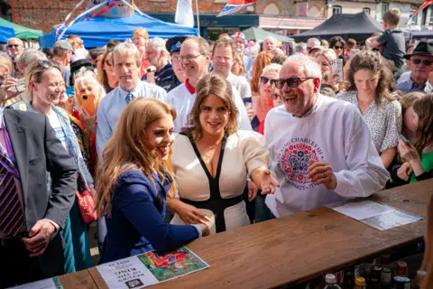 PA Media Princess Beatrice (left) and Princess Eugenie (centre) attend the Coronation Big Lunch in Chalfont St Giles, Buckinghamshire. Thousands of people across the country are celebrating the Coronation Big Lunch on Sunday to mark the crowning of King Charles III and Queen Camilla. Picture date: Sunday May 7, 2023