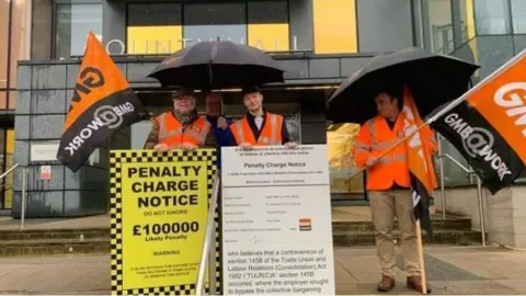 LDRS Three men in orange hi vis vests holding a placard