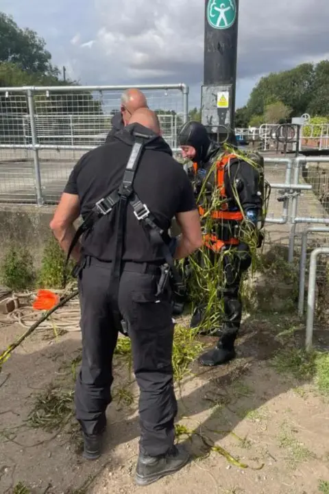 Diver Andy Wiles emerging from Beverley Beck water covered in weeds and in full PPE 