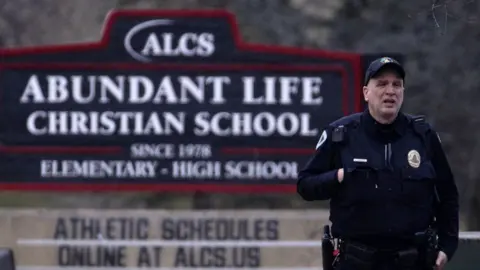 A police officer stands in front of a sign outside the Abundant Life Christian School in Madison, Wisconsin