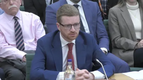 Morgan McSweeney wearing a suit, giving evidence to Foreign Affairs select committee