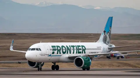 A frontier plane on the tarmac with mountains behind