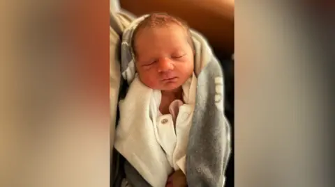 Family handout A baby wrapped in a warm grey blanket.