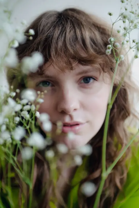 Row Seward Row Seward looking through white flowers at the camera