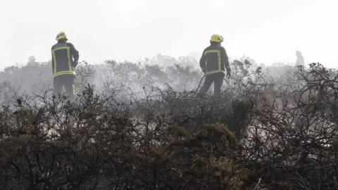 Sue Daly Two fire men attend the blaze on Sark's clifftop