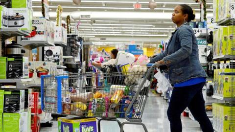 A woman pushes a trolley through a Walmart supermarket