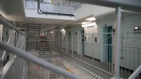 Shaun Whitmore/BBC Inside the Elizabeth Fry wing in HMP Norwich. There are rows of cells on different levels and a secure staircase runs in the middle to connect them.