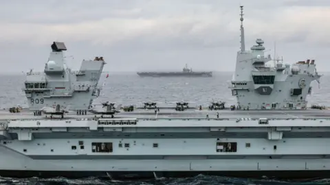 MOD HMS Prince of Wales (foreground) with F-35B Lightning jets on deck and USS Harry S. Truman (background)