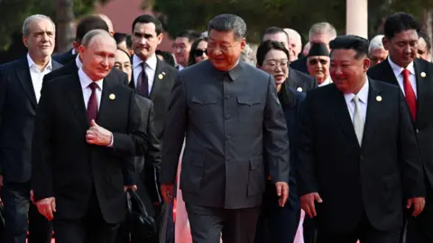 Vladimir Putin, Xi Jinping and Kim Jong Un walking side by side with other world leaders behind them
