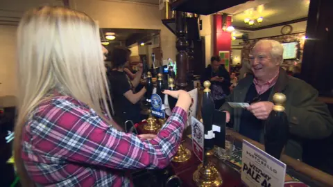 Woman serving beer to a man in a pub