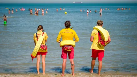 Getty Images Lifeguards stand on duty as swimmers enjoy themselves in the sea at Margate beach in Margate, England.