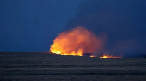 A night-time image of a large fire on Salisbury Plain against an inky blue sky in Wiltshire. 
