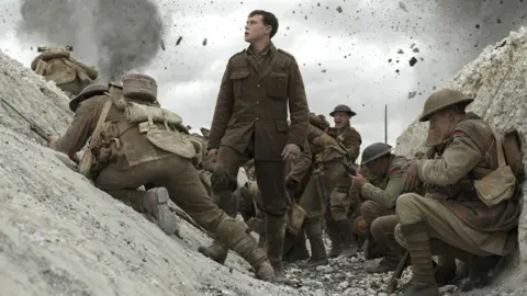 Entertainment One A First World War British soldier looks up as he stands in a trench surrounded by other soldiers while bomb debris flies overhead.
