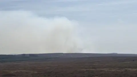 LOUIS REYNOLDS/BBC A view of the moorland fire, with smoke seen billowing in the distance around the moors and fields.