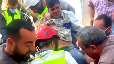 BBC A young man is rescued from the rubble.