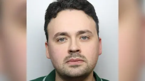 Police mug shot of a man in his early 30s, with dark hair, stubble and a green polo shirt.