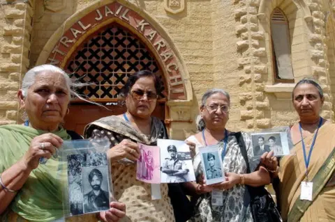 AFP Members of an Indian delegation show pictures of missing Prisoner of War (POW) relatives during a tour of the central jail of Karachi, 04 June 2007