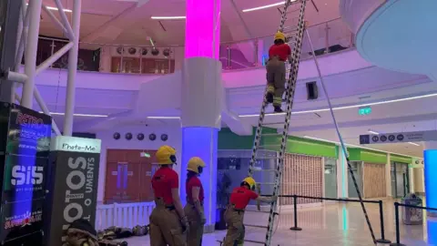 Edd Smith/BBC Firefighters climbing a ladder