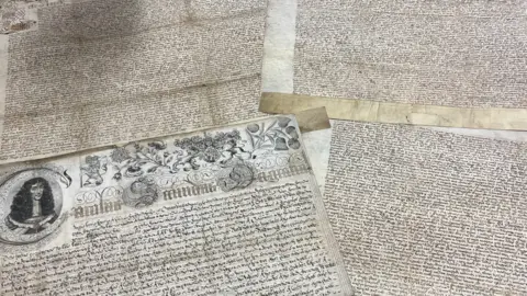 West Yorkshire Archive Service Two Royal Charters granted to the City of Leeds are displayed together on a table