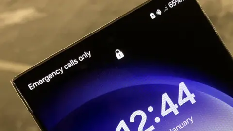 Paul Moseley/BBC The upper-half of the screen of a mobile phone. It tells us it can make 'Emergency calls only' and there is no reception.