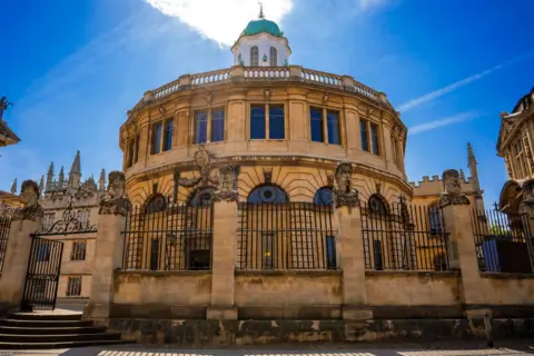 Getty Images The grand circular theatre from outside made in honey-coloured limestone bricks and bordered by high walls with stone heads perched on top.