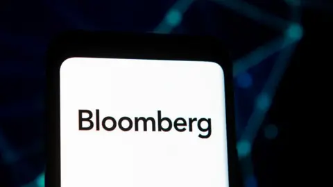 The Bloomberg logo on a phone screen against a black backgound