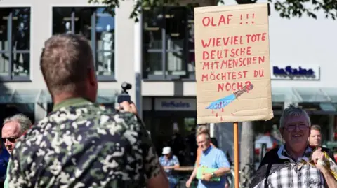 REUTERS People protest following a stabbing attack in Solingen that left several people dead or injured, as German Chancellor Olaf Scholz visits a Social Democrat (SPD) election campaign rally in Jena, Germany, August 27, 2024.