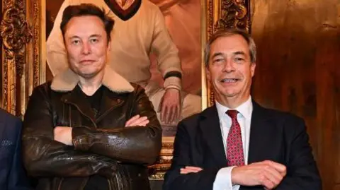 PA Media Elon Musk and Nigel Farage standing next to each other with their arms folded. Mr Musk brown leather bomber jacket with white collar. Farage, who  is smiling at the camera and wearing a dark suit, white shirt and red and blue tie. 