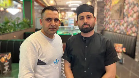 Hijarat Meshwanai and Abdullah Sarkani standing in their restaurant, Afghan Cuisine on Cowley Road.