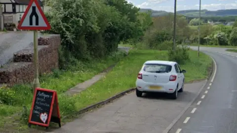 A sign advertising the antiques business at the side of the Malvern Road. 