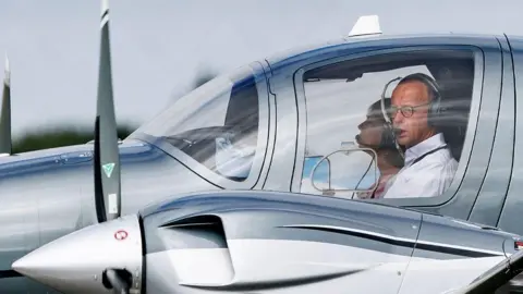 Alamy Friedrich Merz watches from cockpits, carrying headphones and glasses next to another person who is not visible