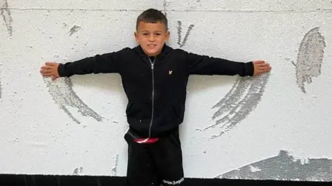 William Brown, 7, standing up against a wall