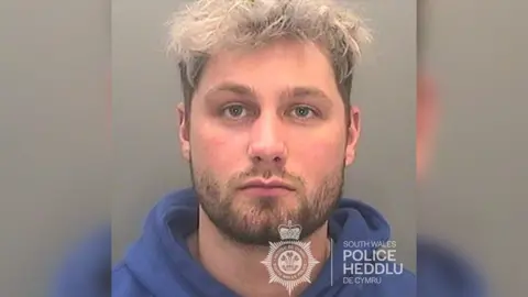 South Wales Police A custody picture of Ricky Perkins wearing a blue hoodie jumper looking at the camera