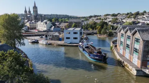 A large boat in the water of Truro Harbour seen from above.