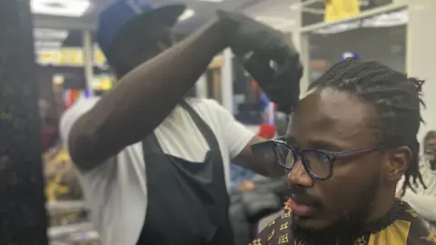 A picture of a barber at work at Roots in Derby with Chimbuomemma Rayme-Nwokah in the chair 
