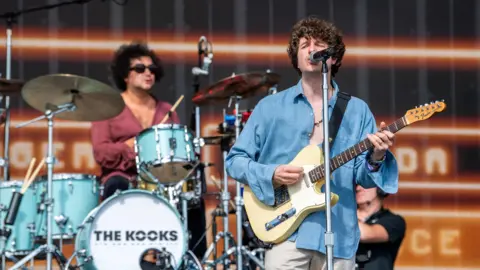 The Kooks performing on a main stage at an event.