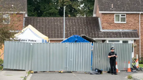 Getty Images A cordon in front of Sergei Skripal's home in March 2018. It's a large metal cordon with a policewoman standing guard outside. 