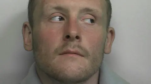 A custody photo of Jason Evans who has short hair and is looking to the side.