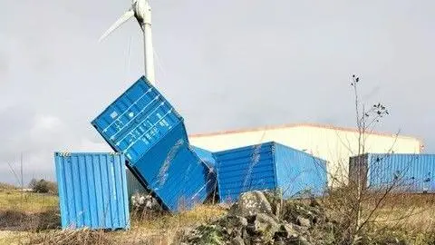 About 4  bluish  shipping containers tin  beryllium  seen connected  the ground, including 1  which has ended up   diagonal and partially resting connected  a instrumentality  adjacent  to it. A ample  gathering  tin  beryllium  seen down  them.