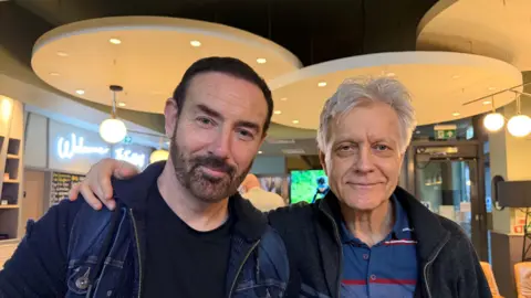 Two men stand in a hotel reception