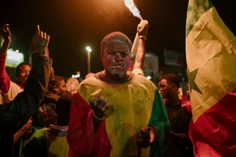 AFP via Getty Images A Senegal supporter celebrates at a fan zone at the African Renaissance Monument in Dakar