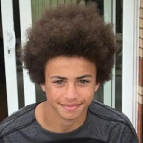 Family photo A boy looking at the camera - he has an afro. It is a head and shoulders shot.